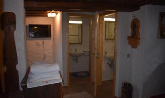 A cozy room with a bathroom area. The walls are light, and there are wooden details as well as towels on a dresser.