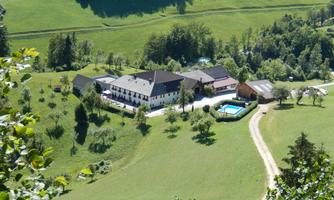 A picturesque landscape with a large building and a pool. Surrounded by green meadows and trees, the environment radiates tranquility and a connection to nature.