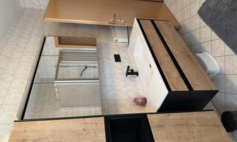 A modern bathroom with a bright tiled floor and a stylish sink. The walls are tiled and a large mirror reflects the space.