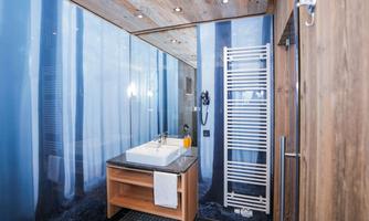 A modern bathroom with a sink and wooden details. The walls are decorated with a calming forest visualization.