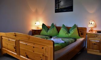 A cozy bedroom with a wooden bed and green cushions. The soft lighting creates an inviting atmosphere.
