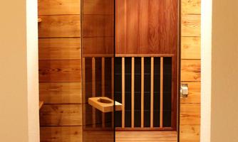 A modern sauna with wooden paneling and a glass door. The interior is designed to be warm and inviting.