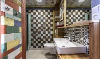 A modern bathroom with an elegant sink and a shower. The walls are decorated with colorful tiles and a striped pattern.