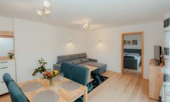 A modern apartment with a cozy living area and a dining corner. The rooms are bright and well-furnished.