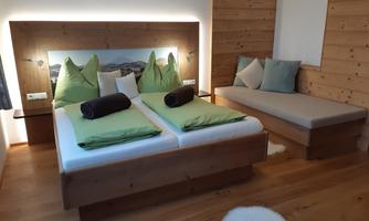 A cozy bedroom with a double bed and a modern wood design. The walls are in warm tones and the pillows provide additional comfort.