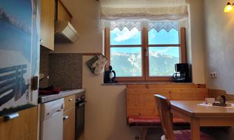 A cozy kitchen with wooden furniture and a view of the mountains. The window lets in a lot of light and creates an inviting atmosphere.
