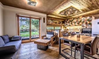 A modern apartment with wooden decor and a cozy dining area. Large windows provide a view of the garden.
