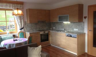 A modern kitchen with wood cabinets and a bright countertop. In the background, there is a window that fills the room with natural light.