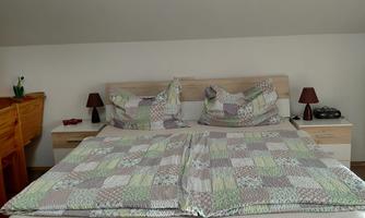 A bedroom with a large bed and colorful bedspreads. Two nightstands with small lamps are also visible.