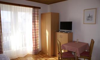 A simple room with a table, two chairs, and a television.  
Large windows let in a lot of light.