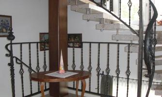 A beautiful entrance area with an elegant staircase and a round table. The walls are decorated with pictures and there is pleasant lighting.