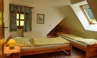 A bright bedroom with two single beds and a large skylight. The walls are simple, and there is a cozy atmosphere with a beautiful window decoration.