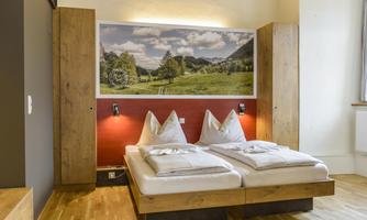 A cozy bedroom with a double bed and wooden furniture. A picture of an idyllic landscape hangs on the wall.