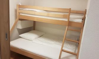 A cozy children's room with a wooden bunk bed. The room has bright and simple furnishings.