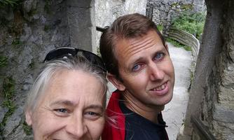 A couple smiles in a historic building. They stand through a stone passage and enjoy the moment.