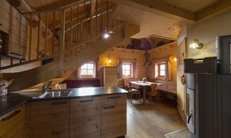 A cozy wooden apartment with stairs, a modern kitchen, and a dining table. The warm wood tones create an inviting atmosphere.