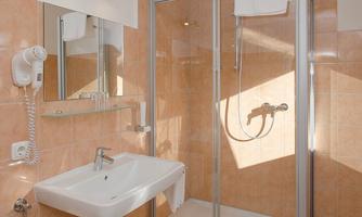 A modern bathroom with a shower and a sink. The walls are tiled in warm, inviting colors.