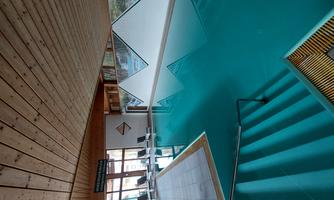 A cozy pool room with clear blue water and modern loungers. Large windows let in plenty of daylight and create a relaxed atmosphere.