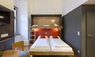 A modern room with a double bed and a bunk bed. There is a small table and a chair, as well as a simple design.