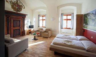 A modern room with wooden flooring, a comfortable seating area, and a large bed.  

Large windows provide plenty of daylight and a beautiful view outside.