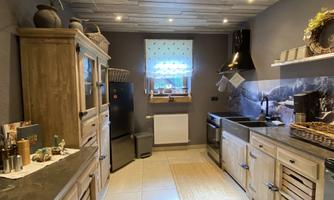 A modern kitchen with wooden cabinets and elegant appliances. The window lets in plenty of light and creates a friendly atmosphere.