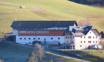A large, multi-story building in a rural setting. It is surrounded by green meadows and features modern architecture.