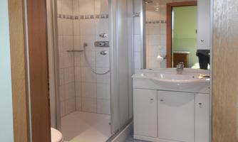 A modern bathroom with a shower and a sink. The walls are tiled, and there is a bright, welcoming atmosphere.