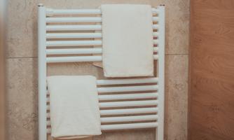 A towel rack in a bathroom with two white towels. The walls are in neutral tones.