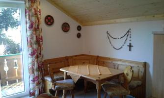 A cozy room with a wooden table and a bench. There is a beautiful view from the window and decorative walls.