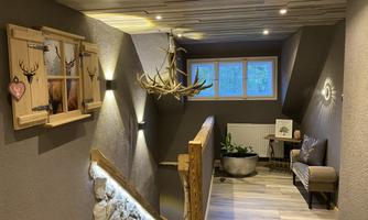 A cozy hallway with wooden elements and indirect lighting. A decoration with a deer antler and plants creates an inviting atmosphere.