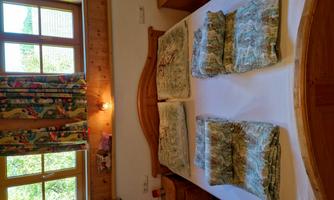 A cozy bedroom with a large bed and decorative pillows. The windows are bright and there are colorful curtains.