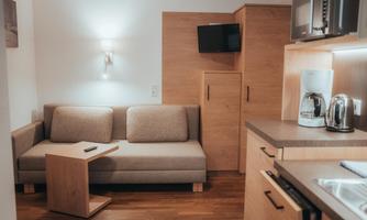 A cozy living area with a beige sofa and a small table. The modern kitchen is well-equipped and creates an inviting atmosphere.