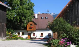 A charming country house with blooming flowers and a perennial bed. Surrounded by green meadows and blue sky.