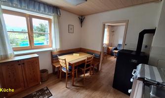 A cozy kitchen with a table and chairs. You can see outside through the window.