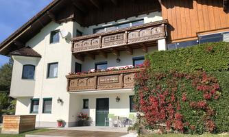 A beautiful residential house with wooden cladding and multiple balconies. Surrounded by green grass and colorful plants, there is an inviting atmosphere.