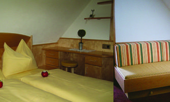 A cozy room with a double bed and a seating area. The walls are light and the furniture is made of wood.