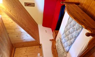 A cozy bedroom with a wooden bed and a red couch. The walls are made of wood, and the room has an inviting atmosphere.