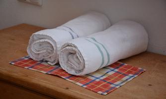 Two rolled towels lay on a checked cloth. The background is bright and kept simple.