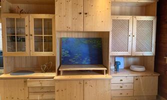 A wooden cabinet with various compartments and drawers. In the middle, there is a picture of water plants.