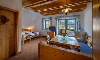 A cozy room with wooden decor, a dining area, and a view of the mountains. The room is bright and friendly, ideal for a stay in nature.