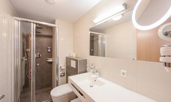 A modern bathroom with a shower and a sink. It has bright walls and a large mirror.