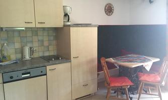 A small kitchen with a table and chairs. The walls are painted in soft colors, and there are various kitchen appliances.