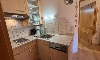 A modern kitchen with wooden cabinets and a bright countertop. There is a stove, a sink, and various kitchen appliances.