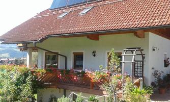 A charming house with a red tiled roof and a cozy balcony.  
Colorful flowers decorate the exterior and create a welcoming atmosphere.