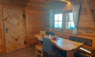 A cozy room with wooden walls and a table for two.  
In front of a window, there are two chairs, and on the table, there are snacks and drinks.
