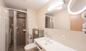 A modern bathroom with a shower and sink. Bright walls and a large mirror create a pleasant ambiance.