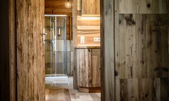 A modern bathroom with a glass shower and wooden paneling. The space has a warm, inviting atmosphere.