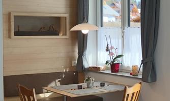 A cozy dining area with a table and two chairs. The window lets in plenty of light and a plant is on the table.