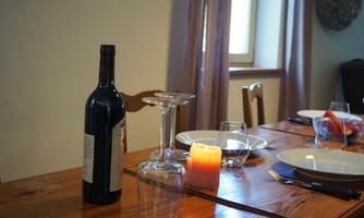 A beautifully decorated table with a bottle of red wine, glasses, and a candle. The setting feels cozy and inviting.