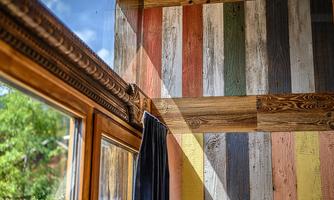 A room with colorful wooden paneling and a large window. There is a brown curtain framing the view outside.